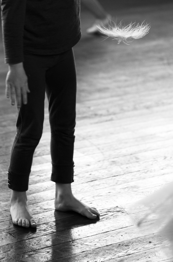 A black and white image of a person standing on a wooden floor about to dance.