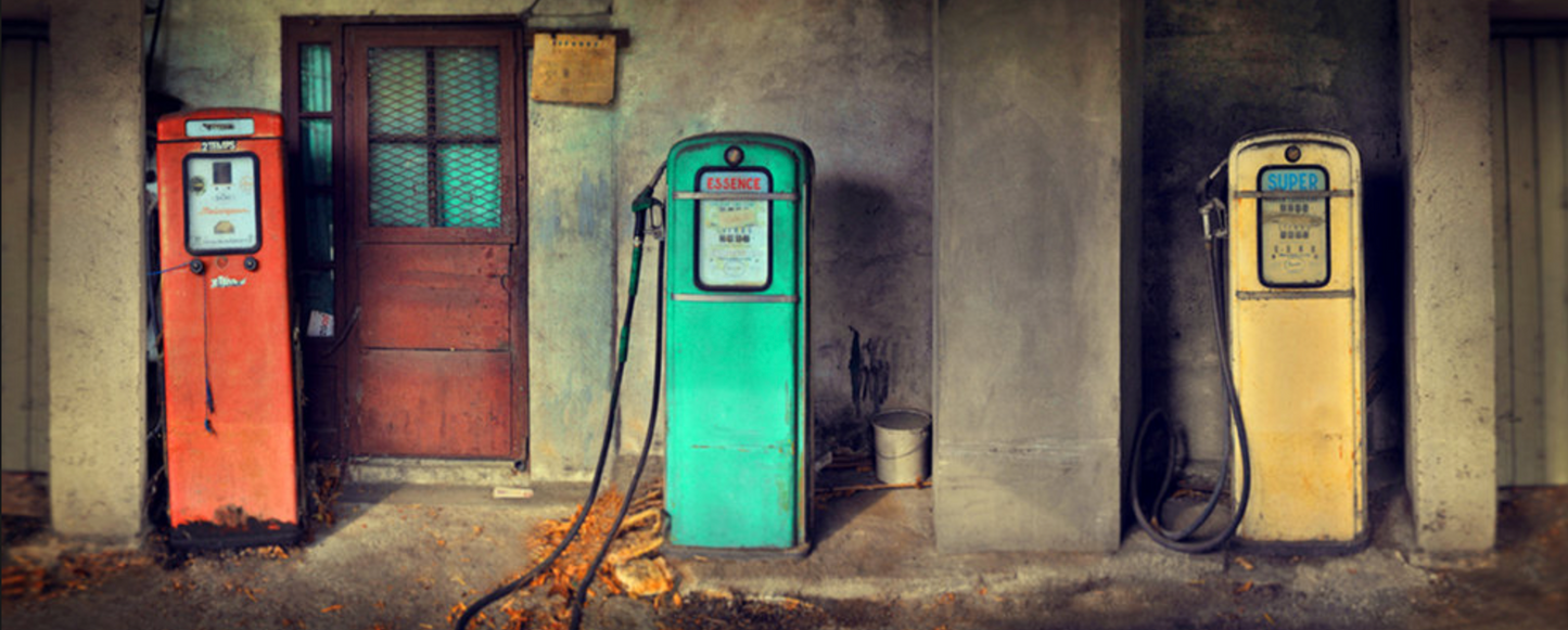 A photograph of three differently colored vintage gas station pumps