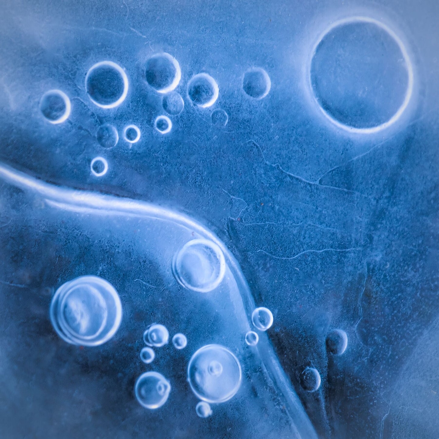 A blue abstract artwork featuring various circles and circles on a dark background.