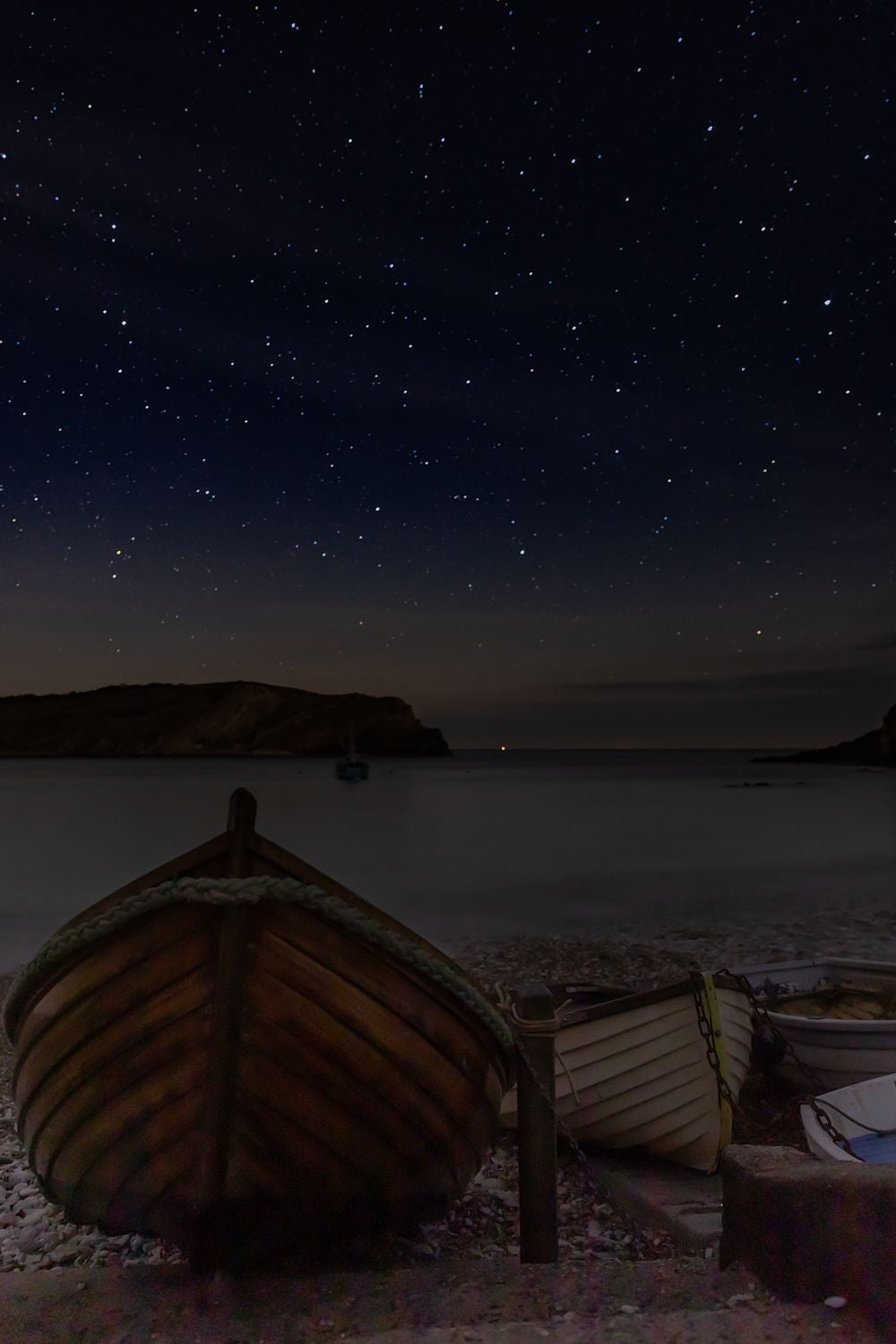 an image of a stary night with a boats in a shoreline and a ship on a body of water.