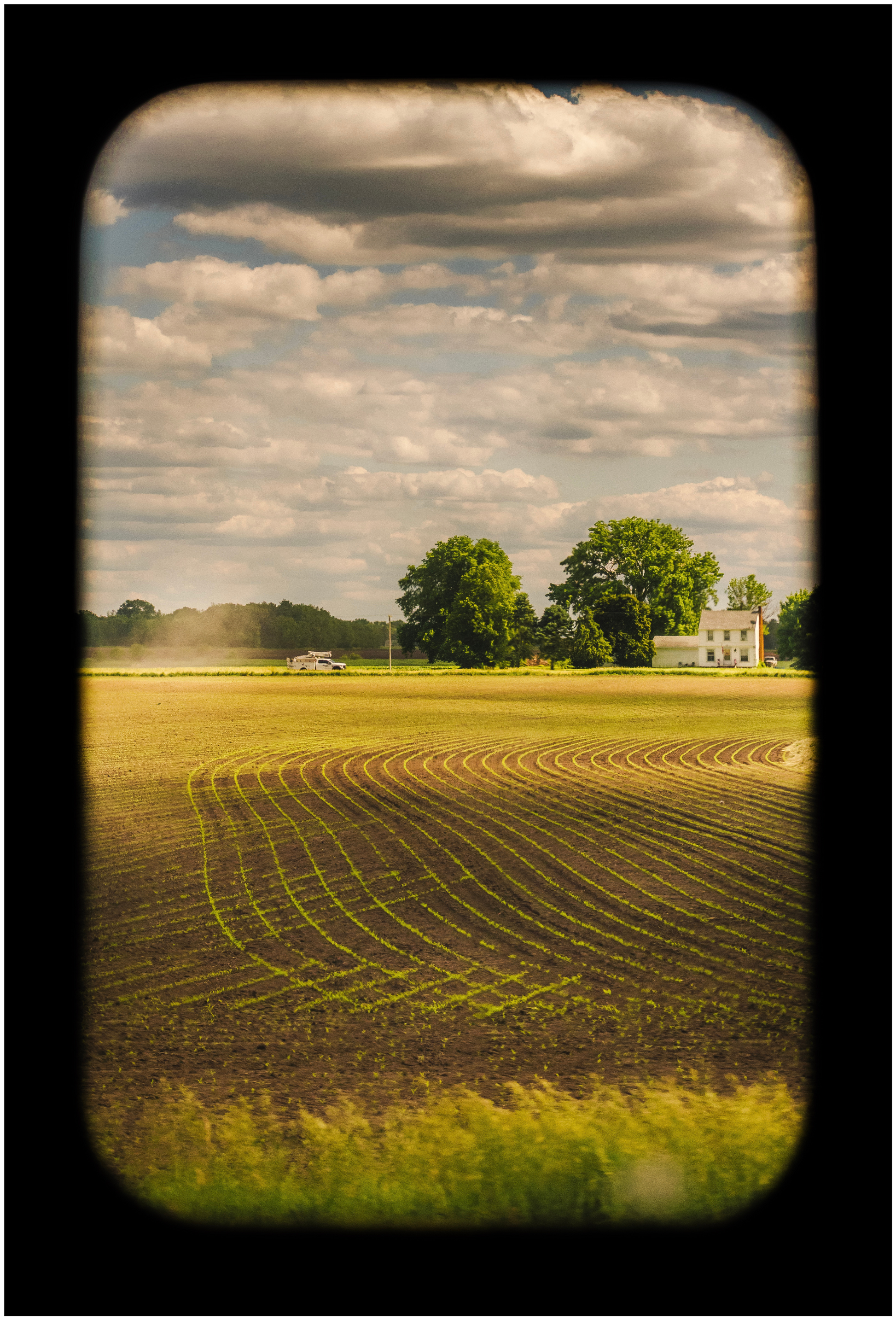 A printed photograph depicting a field under a cloudy sky, part of a series titled 'Portrait of America'.