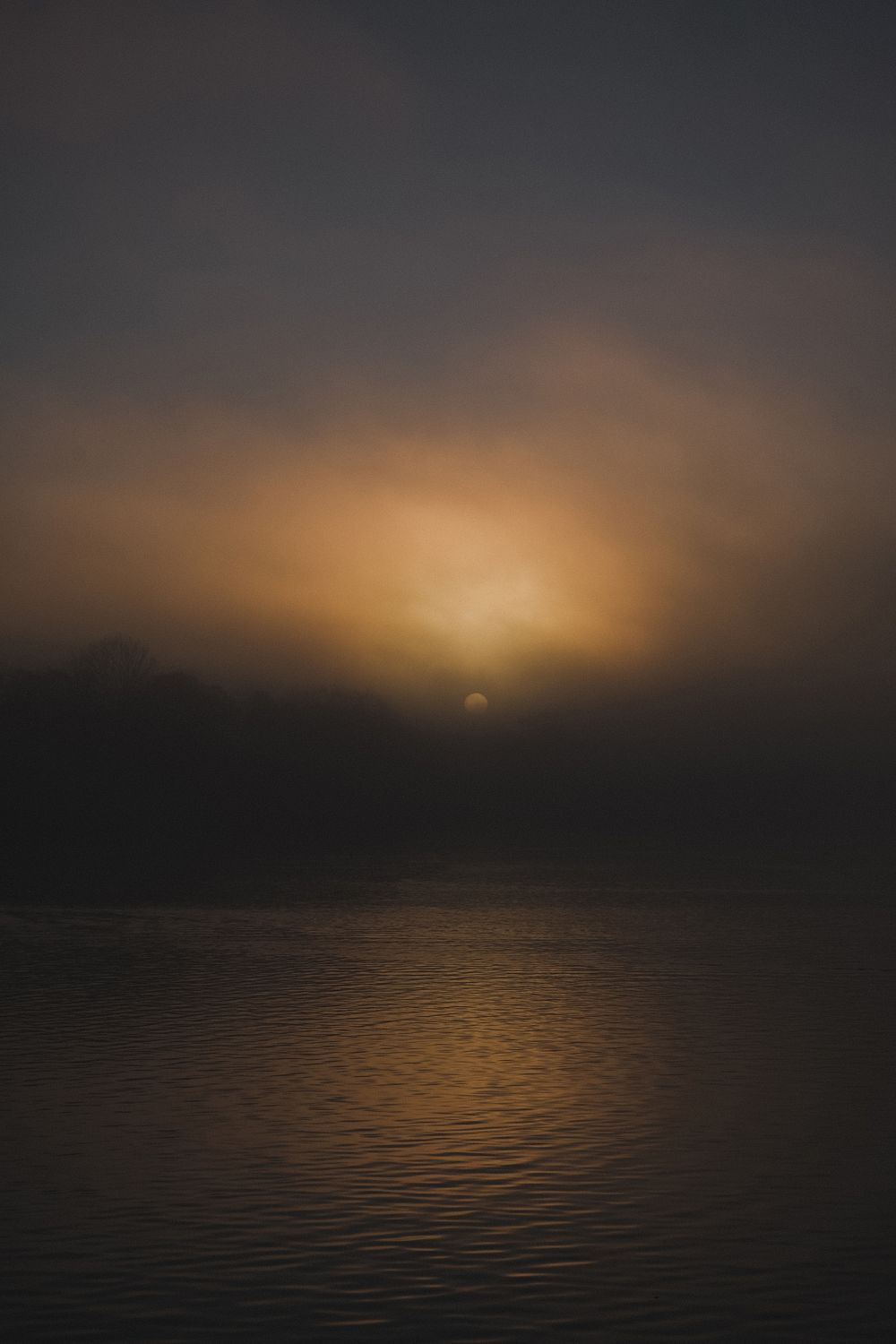 A photograph featuring a sunset over a body of water, with a warm glow over the landscape.