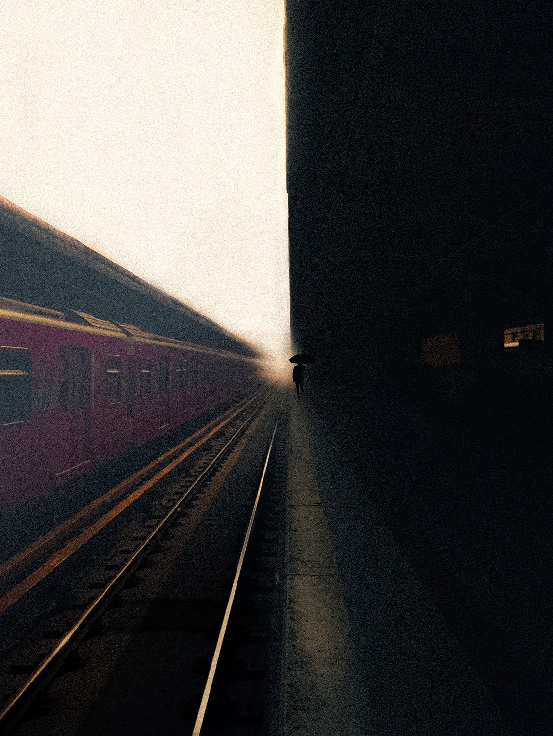 A  photograph of a motion blurred train station with a figure standing on the platform.