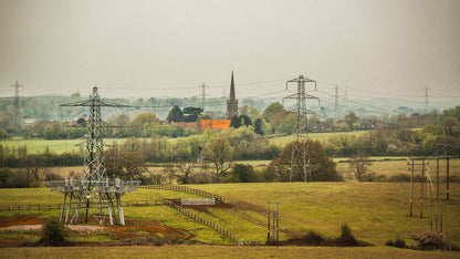A fine art print featuring a rural landscape with power lines, a church, and a red-colored house.