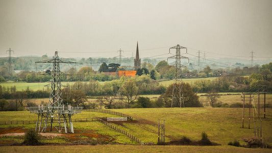 A fine art print featuring a rural landscape with power lines, a church, and a red-colored house.