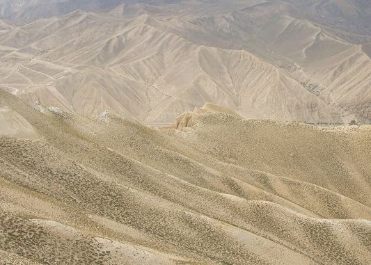 A landscape photo featuring a rugged, mountainous terrain in a brownish-beige color palette.