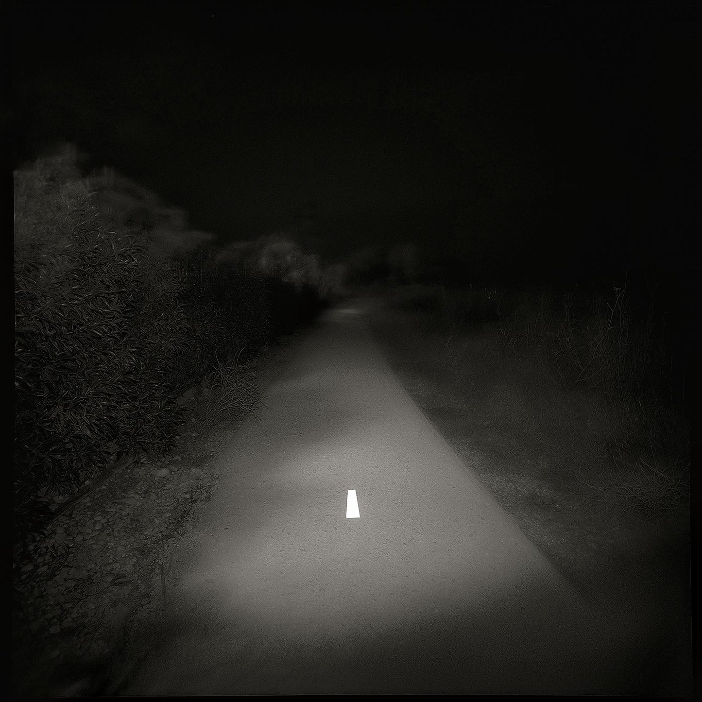 A black and white photo of a lonely road with a white line in the center, printed on a Giclée Hahnemühle photo rag.
