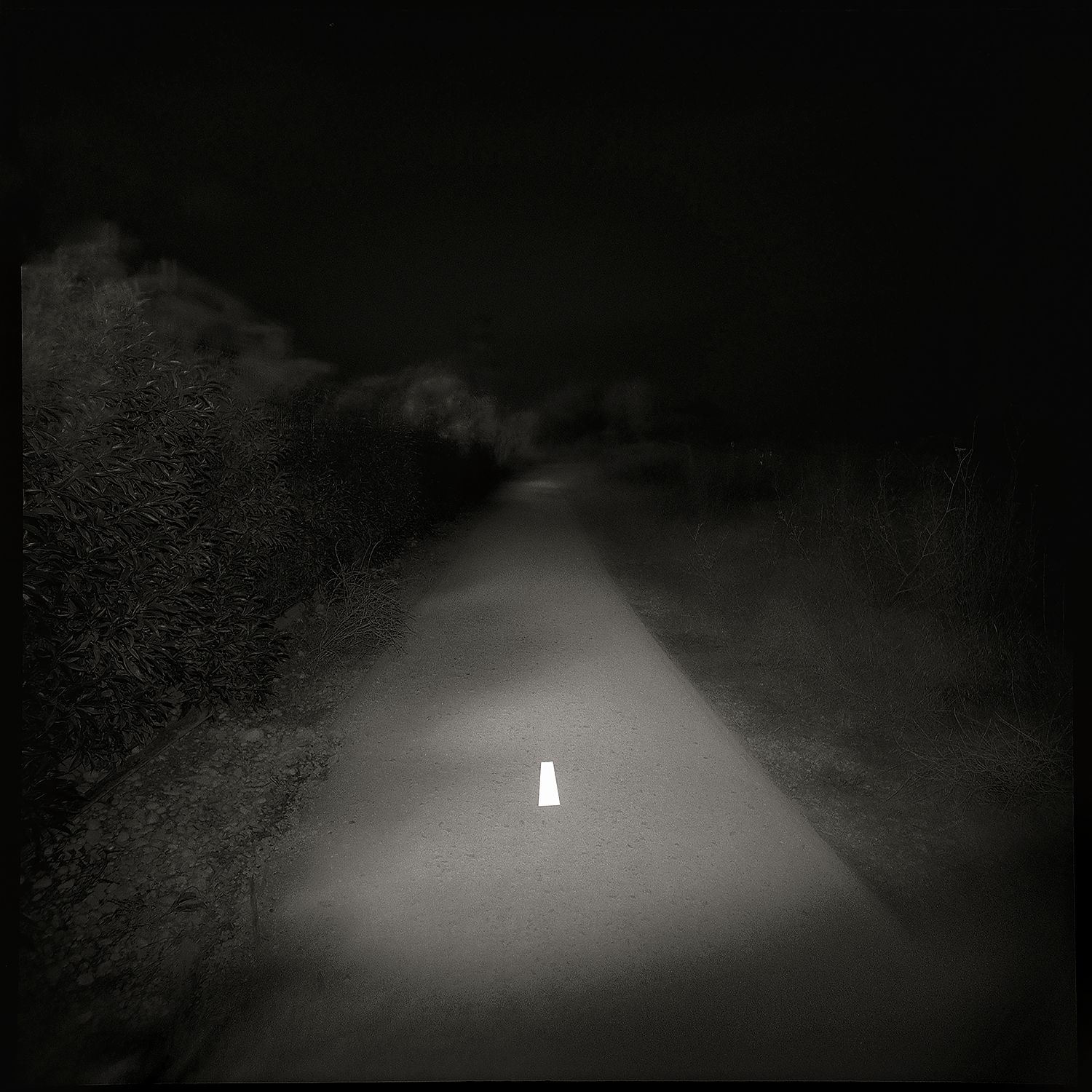 A black and white photo of a lonely road with a white line in the center, printed on a Giclée Hahnemühle photo rag.