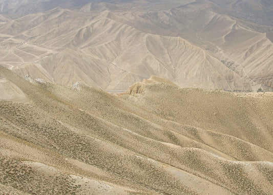 A landscape photo featuring a rugged, mountainous terrain in a brownish-beige color palette.