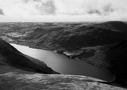 A black and white image of a mountainous region with a water body in the valley 