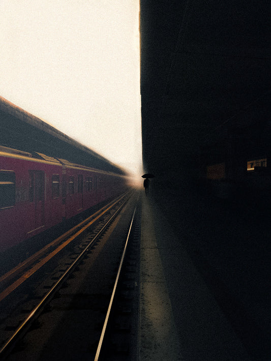 A  photograph of a motion blurred train station with a figure standing on the platform.