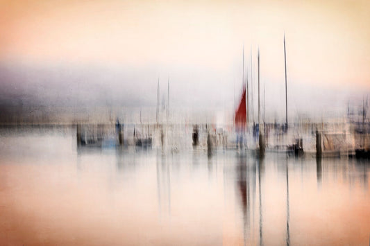A blurred image of a marina with multiple boats and a red sailboat in the foreground.