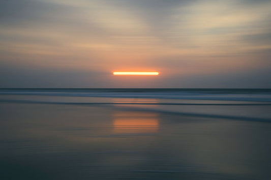 A fine art photograph featuring a sunset or sunrise with a long exposure effect on the shoreline.
