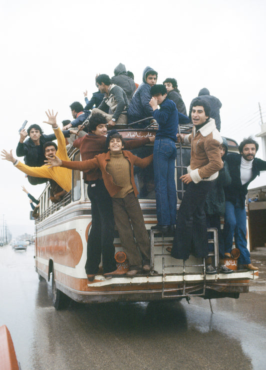 A group of people celebrating and boarding a bus, raising their arms and enjoying the moment.