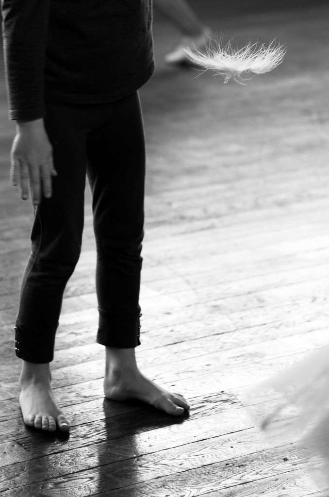 A black and white image of a person standing on a wooden floor about to dance.