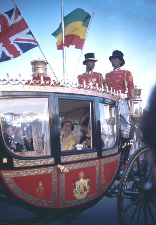 A photograph of the queen of England with the emperor of Ethiopia riding a red and golden carriage.