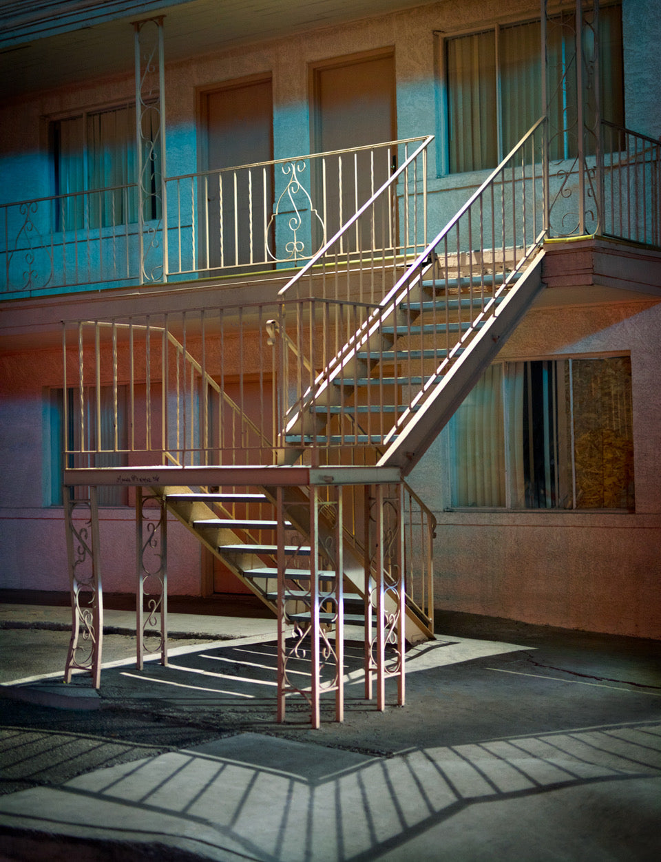 A photograph of a motel staircase at night with a warm lighting, showcasing a minimalist design.