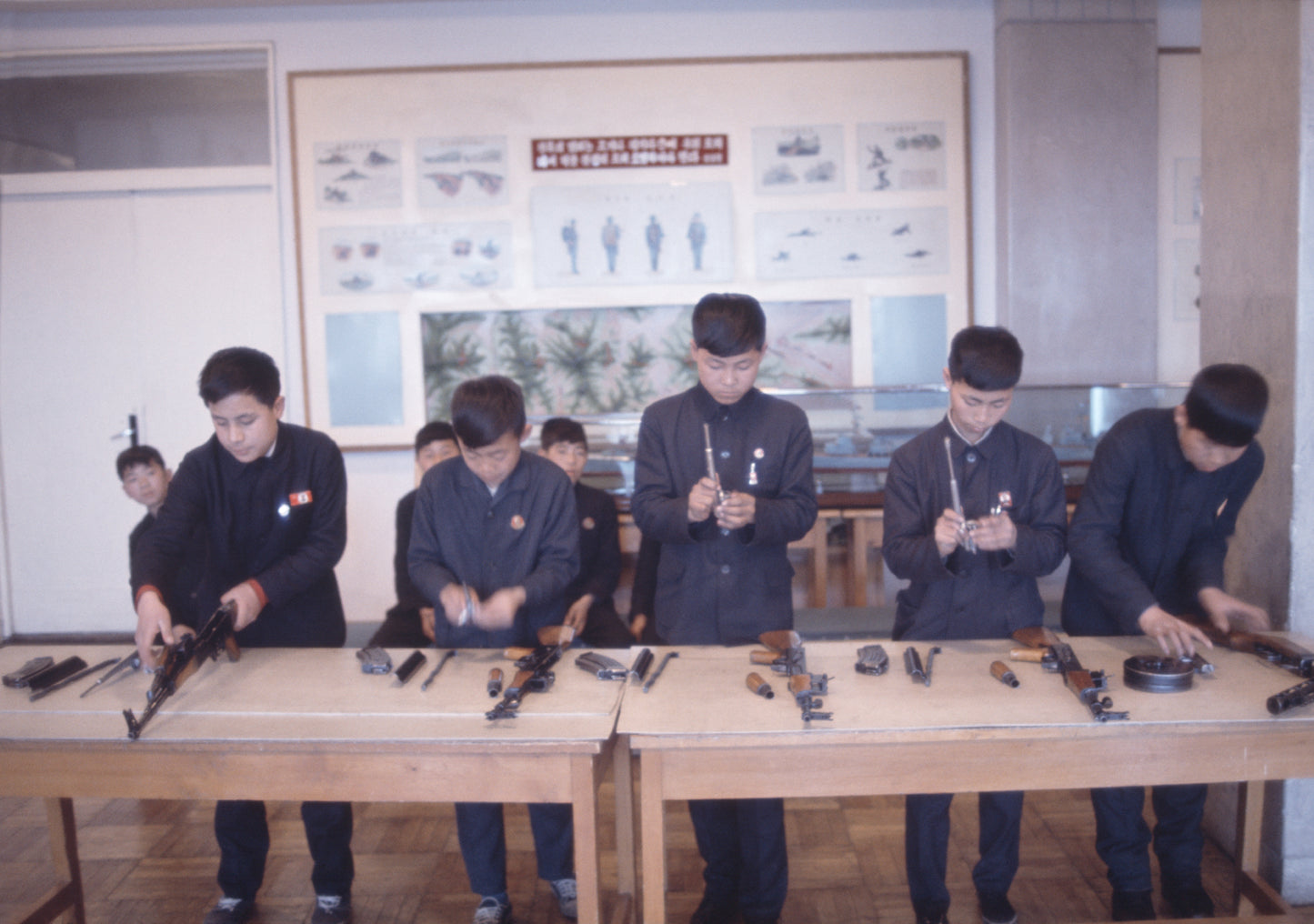 A photograph of children assembling what seems to be fire arms.