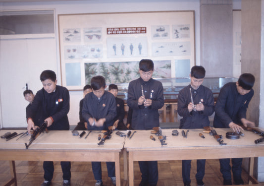 A photograph of children assembling what seems to be fire arms.