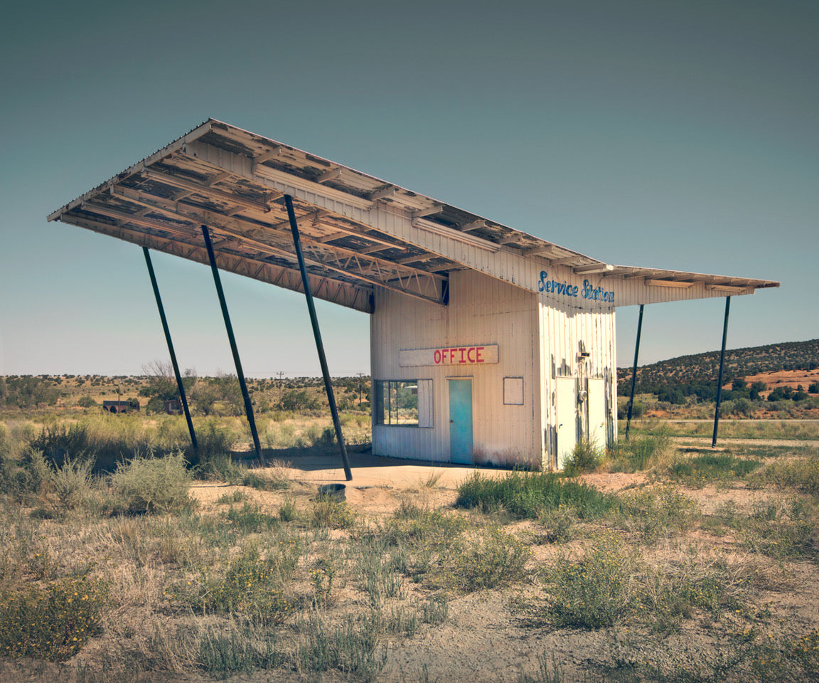 A photograph building in a remote field with an overhanding roof for shade with the word "office" written on it