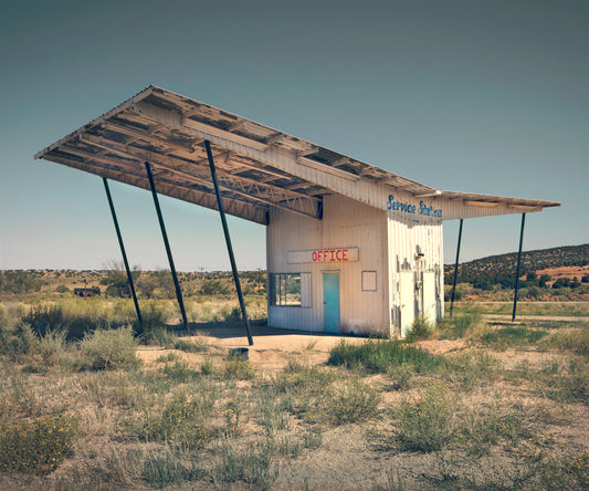 A photograph building in a remote field with an overhanding roof for shade with the word "office" written on it