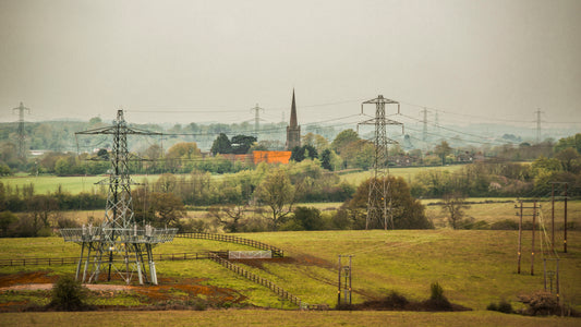 A fine art print featuring a rural landscape with power lines, a church, and a red-colored house.