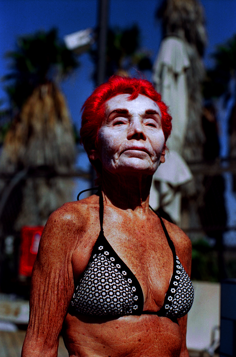 A photograph of a person with red hair and a neutral facial expression, wearing a swimsuit.