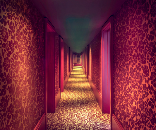 A photograph of a hallway with red floral wallpaper and red accents on the doors and walls
