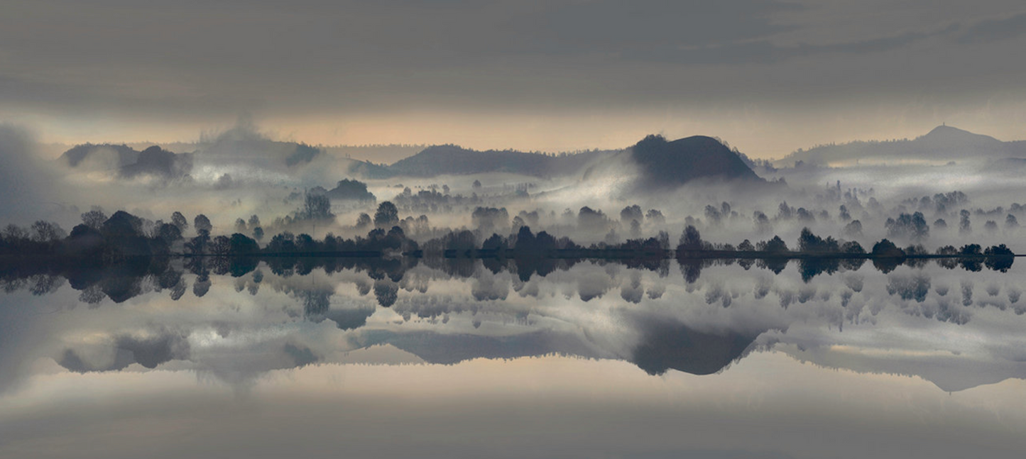 A photographic art print featuring a misty landscape with trees and hills.