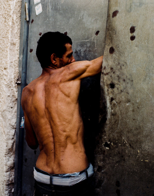 A photograph of a person viewed from behind, against a textured background.