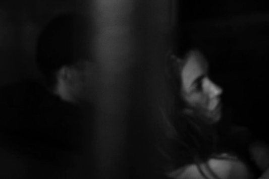 A framed artwork featuring a blurred image of a person's face, primarily in shades of black and white, with a visible portion of a hat and a shadow on the face.