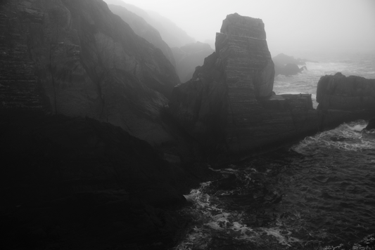 A black and white image of a coastal landscape with cliffs and a body of water.
