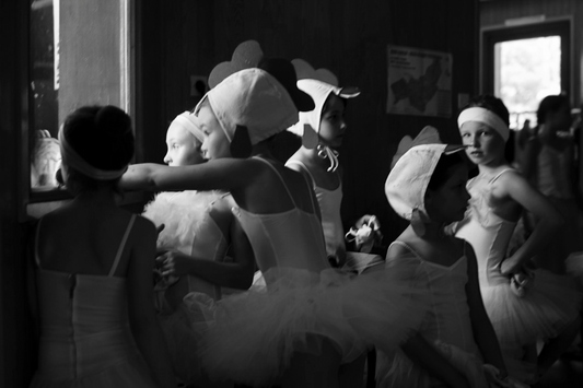 A black and white image of young girls in white tutus with headwear, resembling a scene from a play or a ballet production.