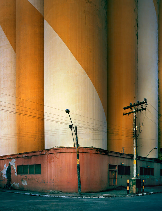 A photograph featuring a twisted silo with a yellowish tint and power lines in the foreground.
