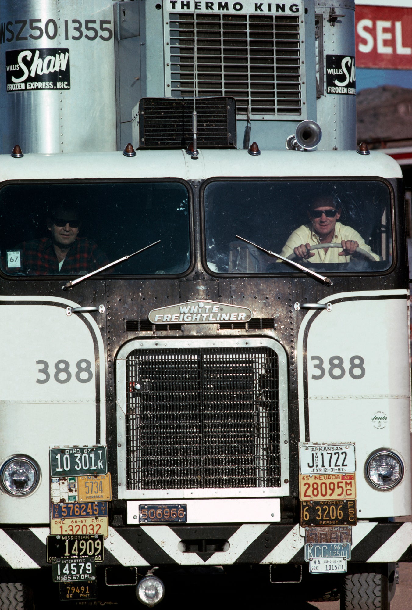 An image of two men driving in a white truck