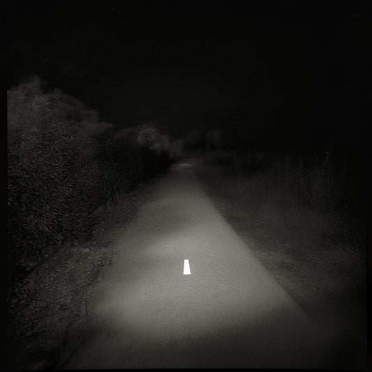A black and white photo of a lonely road with a white line in the center, printed on a Giclée Hahnemühle photo rag.